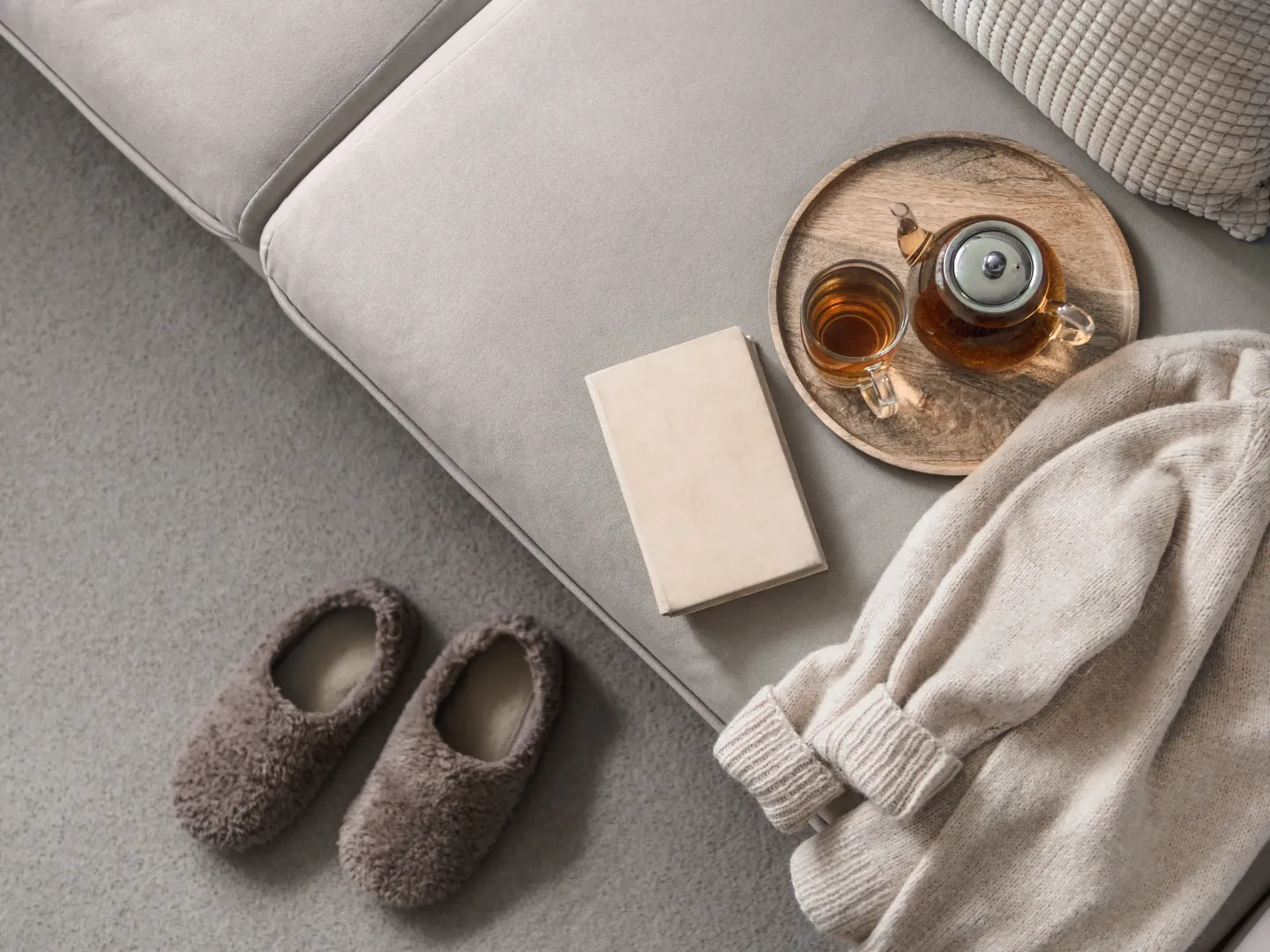 Tagesrückblick Abendgebet: Eine Teekanne, ein Büch und Hausschuhe vor einer Couch