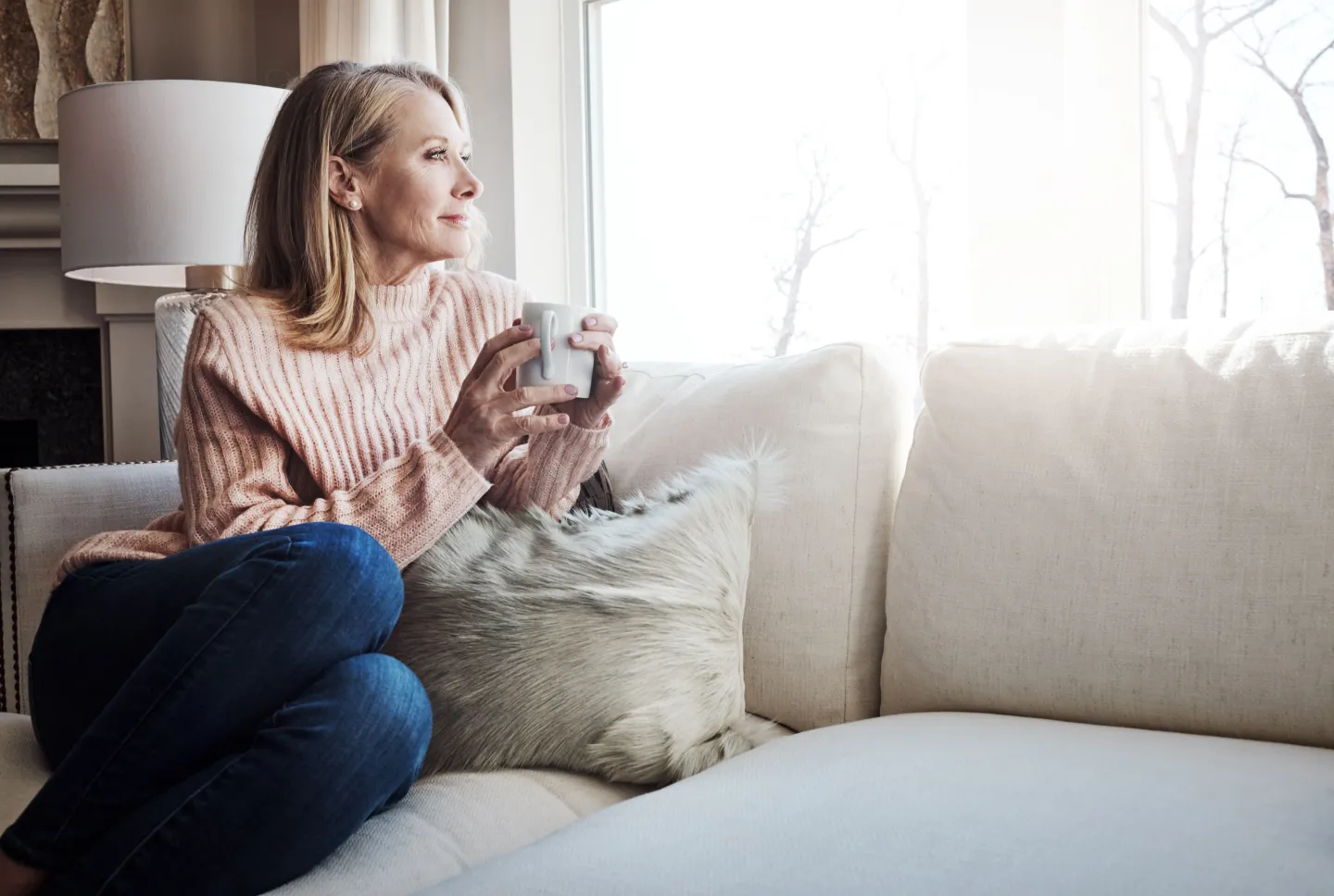 Tagesrückblick. Eine ätere Frau sitzt mit einer Tasse auf dem Sofa