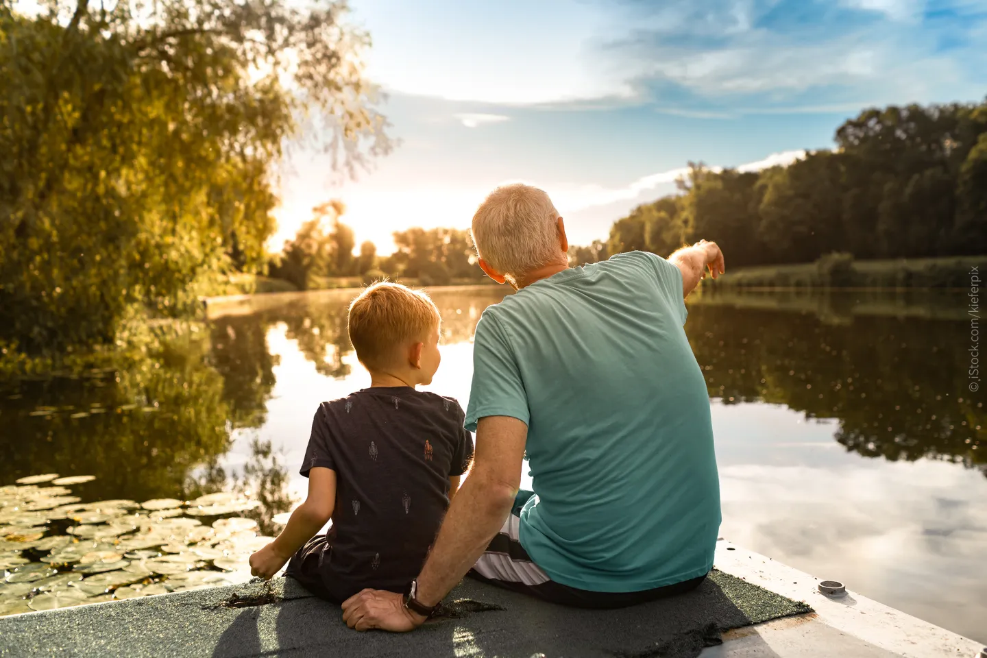 Ein Senior sitzt mit seinem Enkel am See